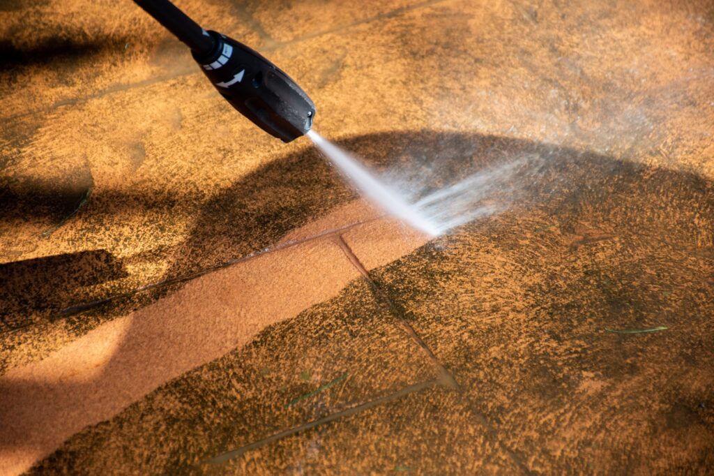 Washing the backyard tiles with high pressure cleaner